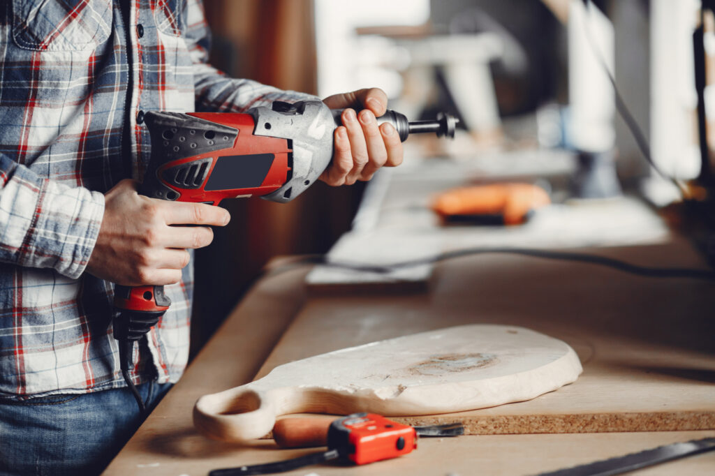 Man using a power tool while working on a woodworking project, demonstrating practical use of power tool rentals for home improvement tasks